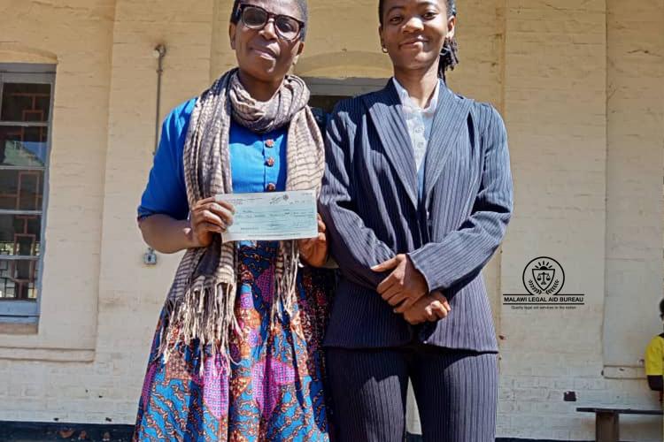 Rasha (left) proudly posing beside counsel while carrying her cheque
